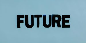 A humanoid robot sitting in front of a laptop in a modern office, representing the Decision Architect role in 2026.