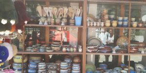 A warehouse worker in 2026 using a digital tablet to manage a fleet of autonomous humanoid robots in a futuristic logistics center.