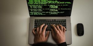 A human hand hovering over a red emergency stop button in a futuristic high-tech control room.