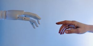A human hand holding a robotic hand, symbolizing digital mercy and trust in 2026.