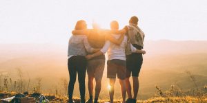 A diverse group of people stacking their hands together in a circle symbolizing community and human connection in a post-AI world.