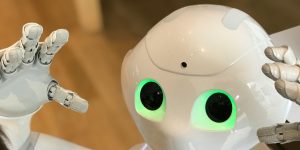 A white robot looking down, representing humanoid fatigue in 2026.