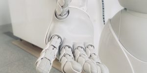 A white humanoid robot standing in a retail environment, illustrating the automation of front-of-house roles.